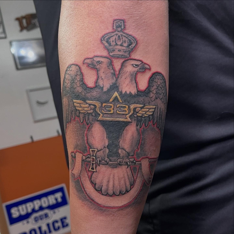 A double-headed eagle with “33” adorned in the middle tattooed on an arm
