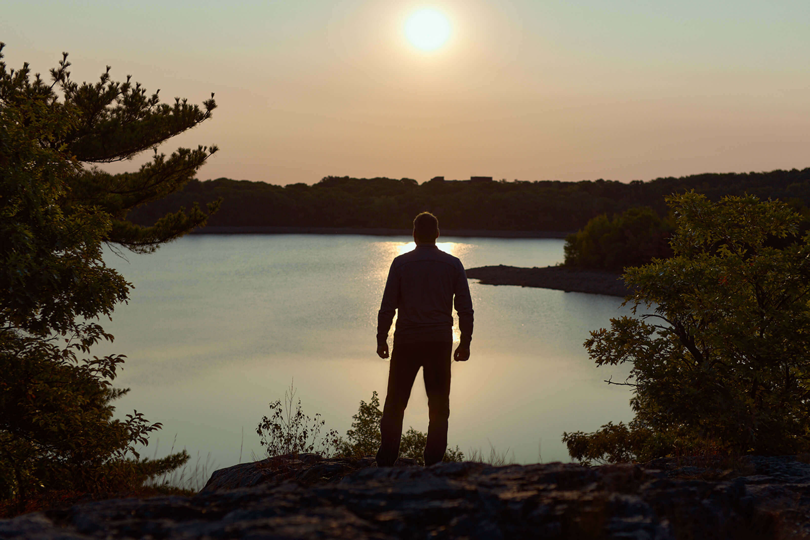 Man standing on cliff watching sunrise
