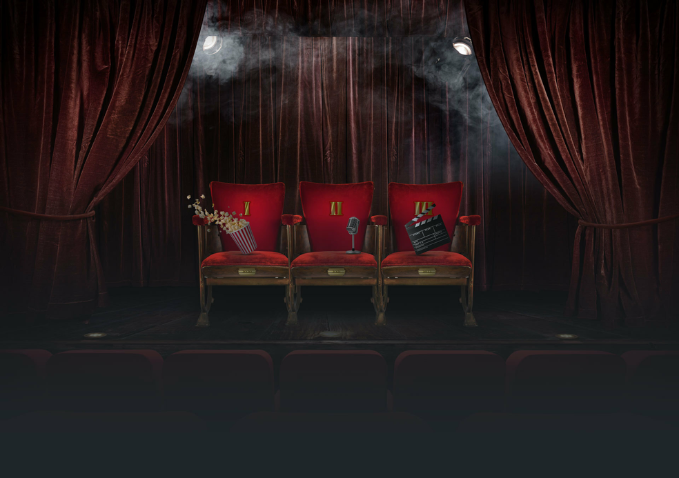 three velvet chairs on a stage with popcorn, clapperboard, and microphone
