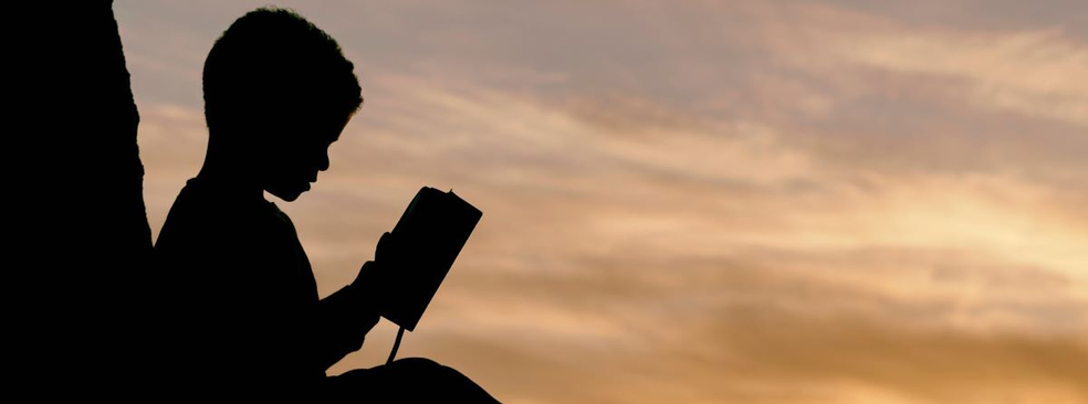 Child reading sunset