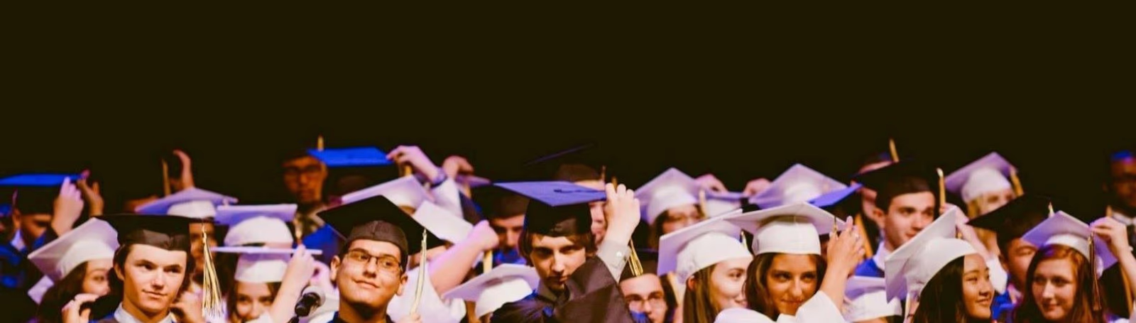 high school grads adjusting their graduation cap tassels at graduation ceremony