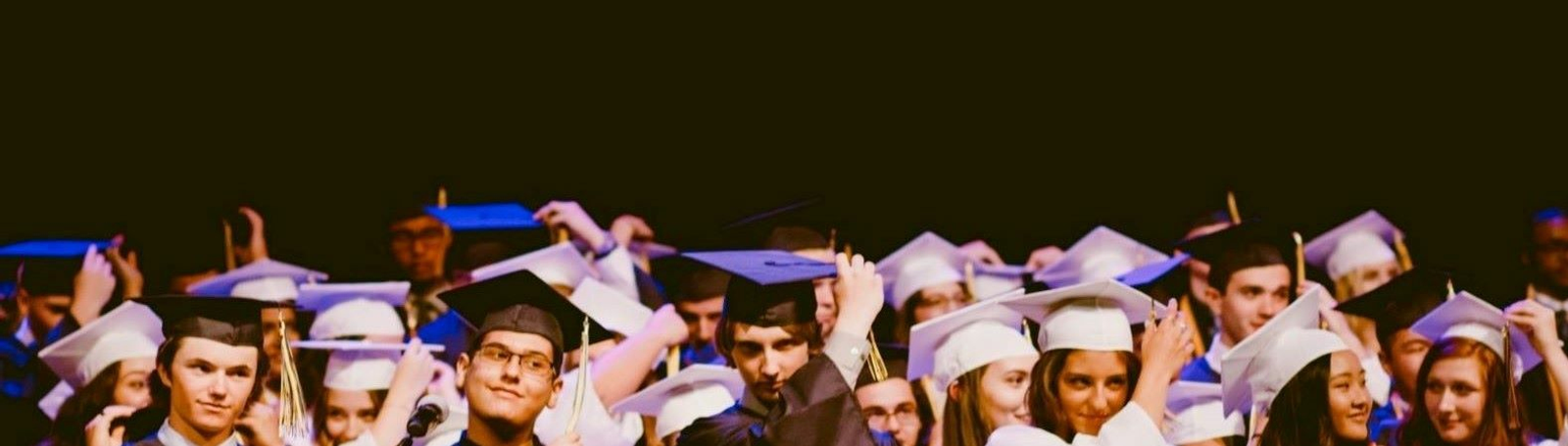 high school grads adjusting their graduation cap tassels at graduation ceremony
