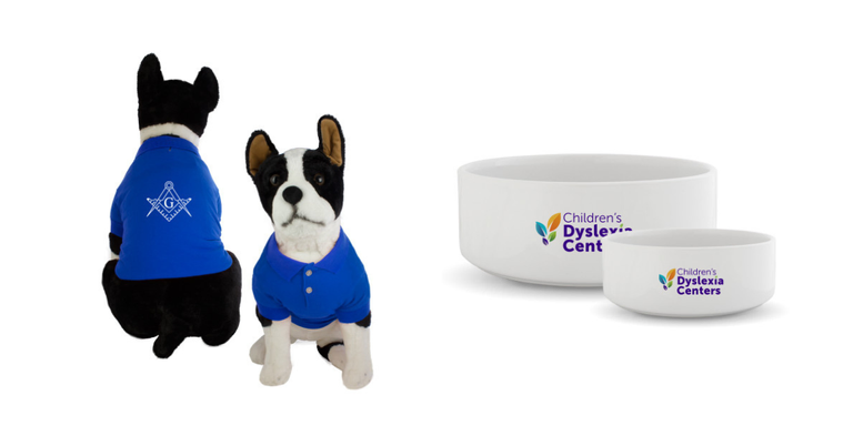 A blue dog polo adorned with the square and compasses and a white dog bowl adorned with the Children's Dyslexia Centers logo