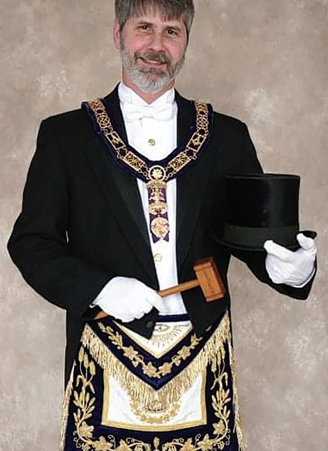 A man standing in Masonic regalia, smiling for the camera.