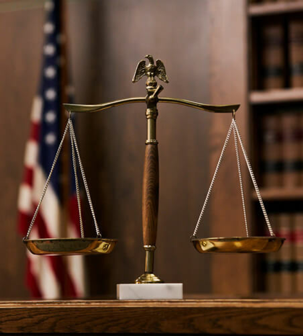 two scales of justice with flag in the background