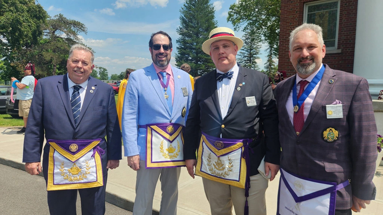 Four Scottish Rite Masons standing together outdoors each wearing purple and yellow formal Masonic regalia