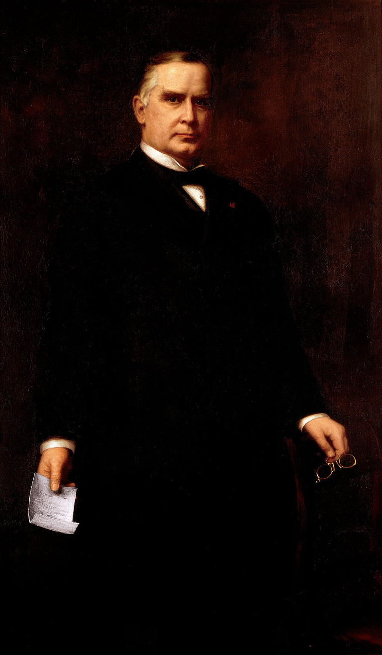 Portrait of William McKinley, standing and holding his glasses and a note
