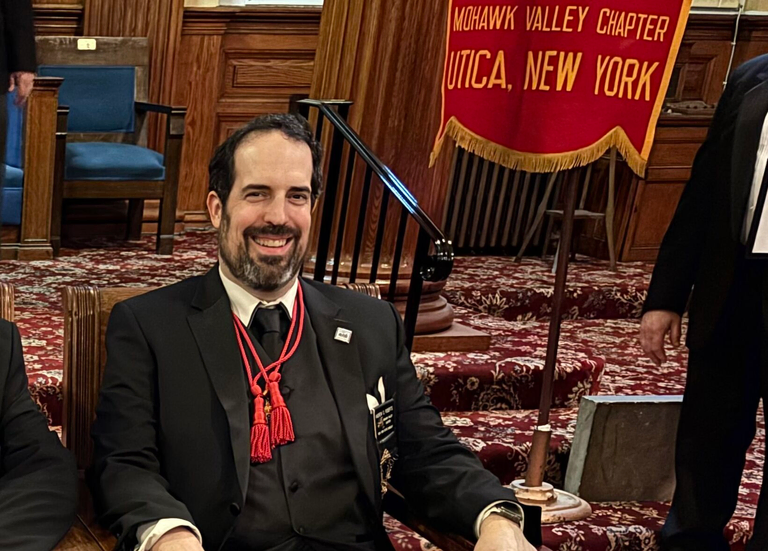 Scottish Rite Masons from the Valley of Utica sit in chairs during a Masonic meeting