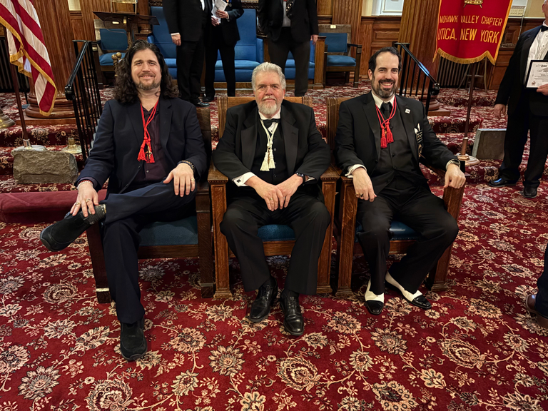 Scottish Rite Masons from the Valley of Utica sit in chairs during a Masonic meeting