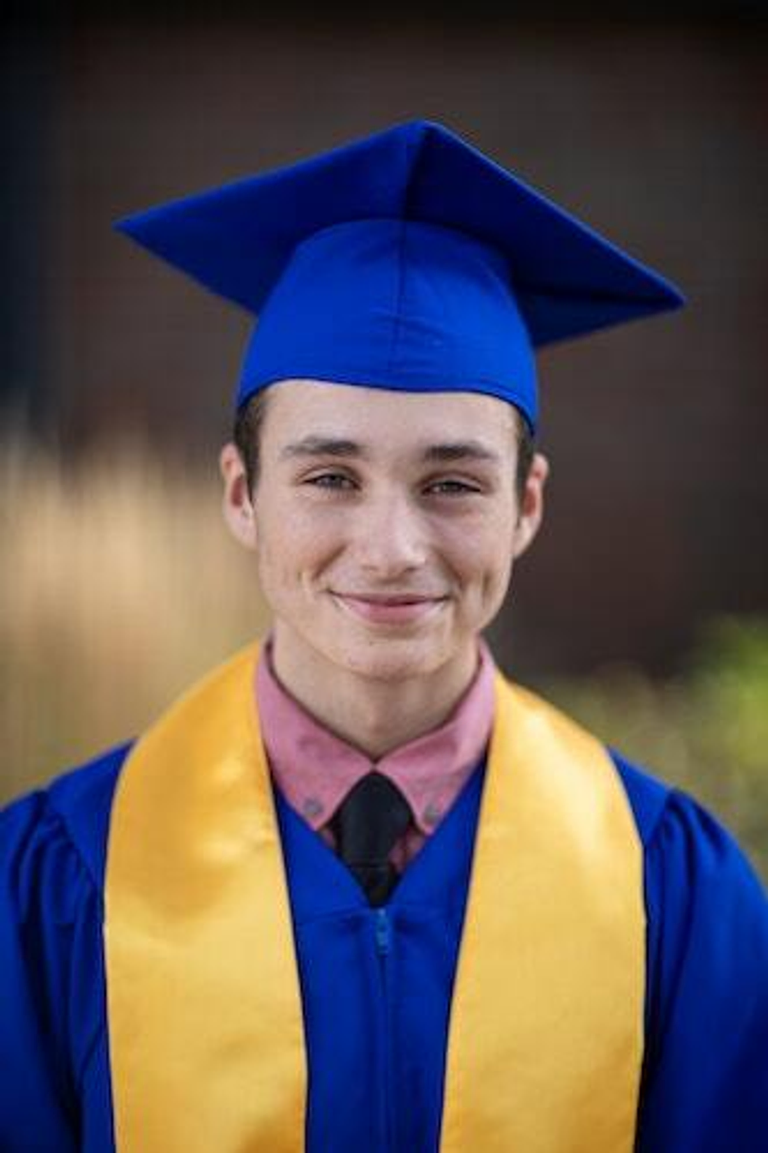 A young man in a graduation cap and gown.