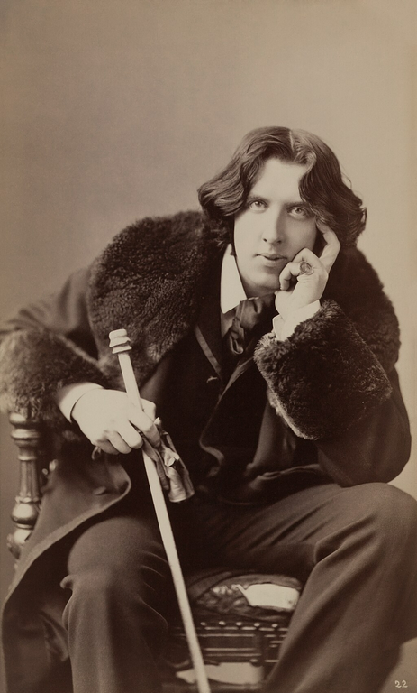 Portrait of Oscar Wilde sitting wearing a fur coat