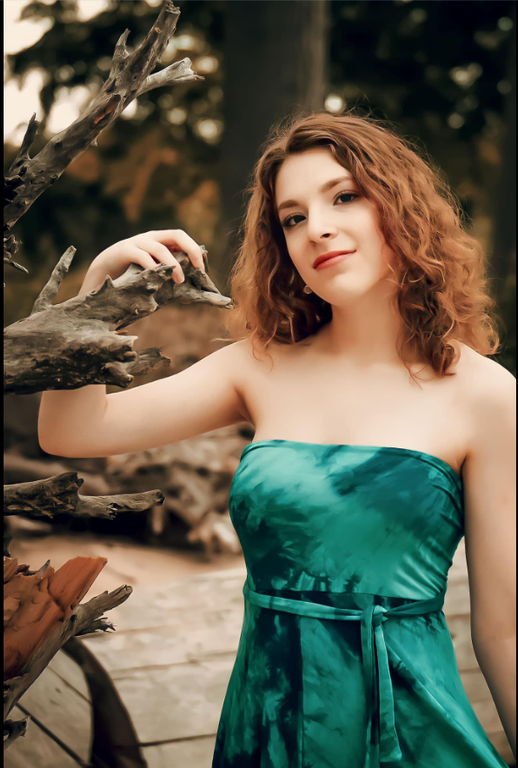 A photo of a Scottish Rite, NMJ Abbott Scholarship recipient wearing a green dress outside holding a tree branch