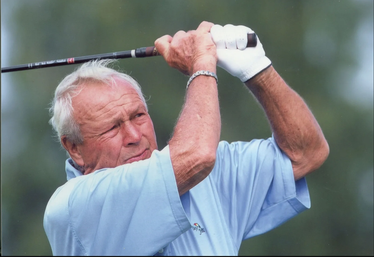 An image of an older Arnold Palmer, shot from the chest up, swinging a golf club