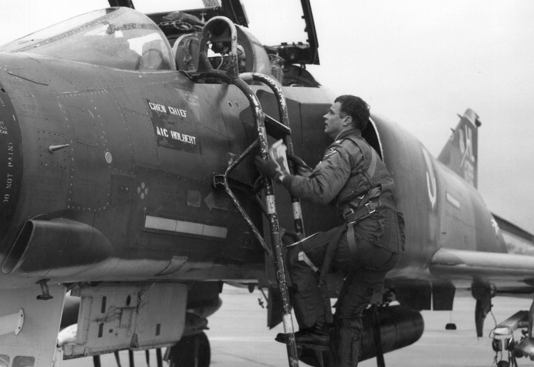 A black and white photo of a pilot entering an F-4 airplane