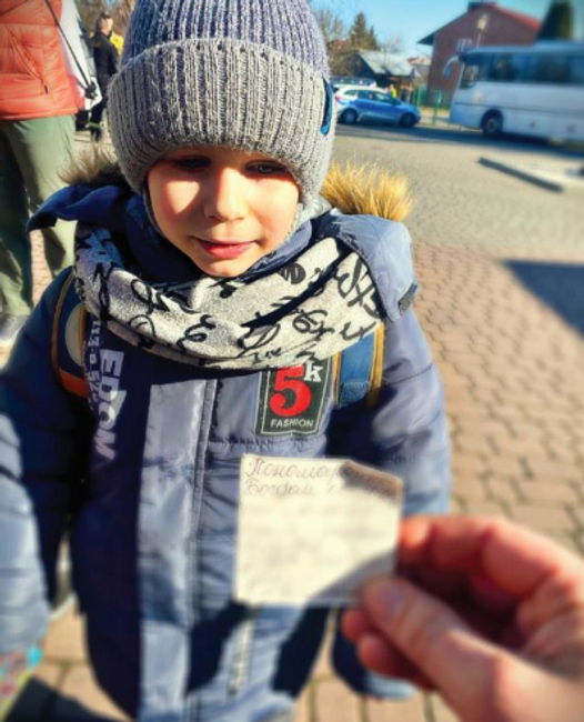 A photo showing a Ukranian refugee child and a Freemason holding their identification in front of them