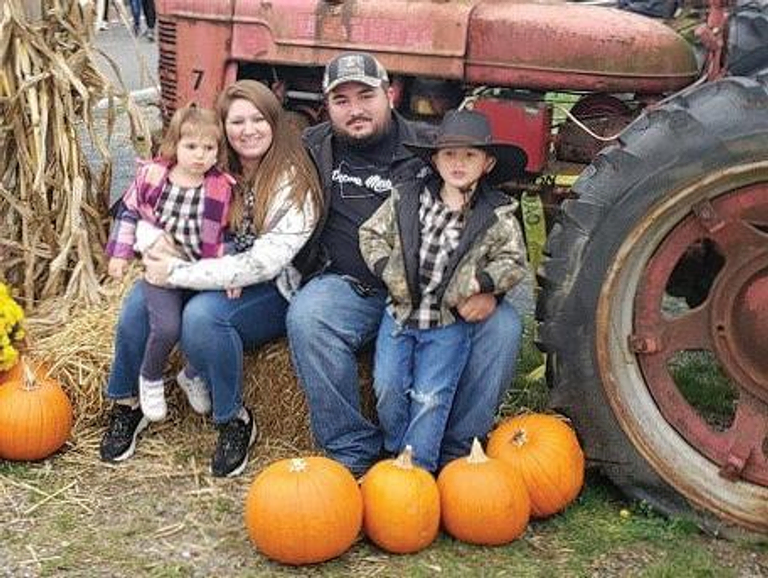 A man, woman, and two children sitting on a haystack