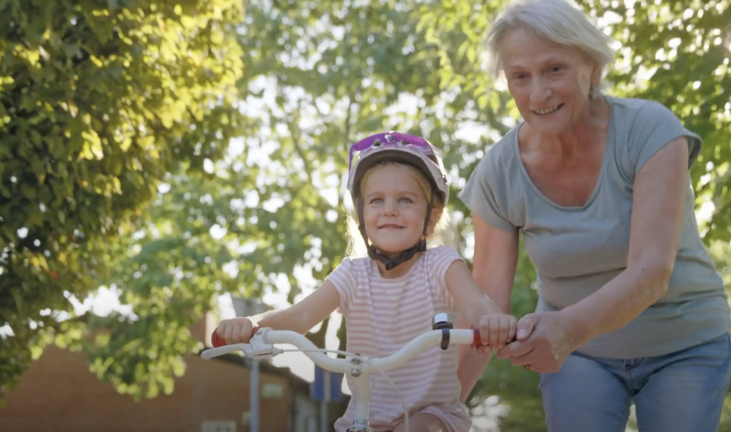 Grandmother helping a child ride a bike