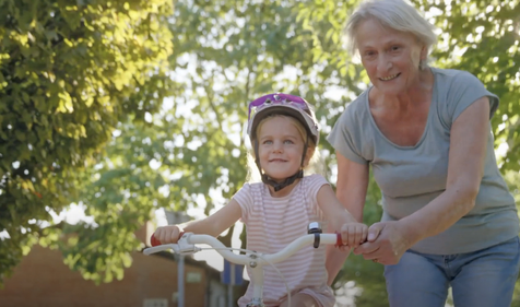 Grandmother helping a child ride a bike